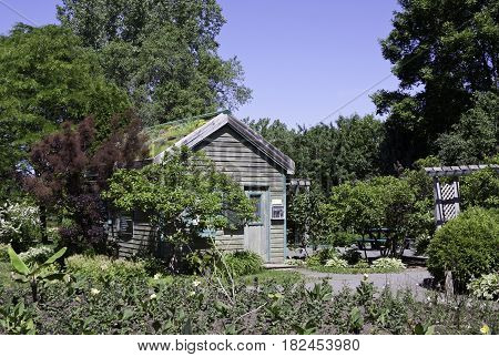 Laval, Quebec - June 14, 2015 - Landscape view of a small wooden garden house surrounded by trees foliage and a small garden in the Nature Park, Laval, Quebec on a sunny day in June.