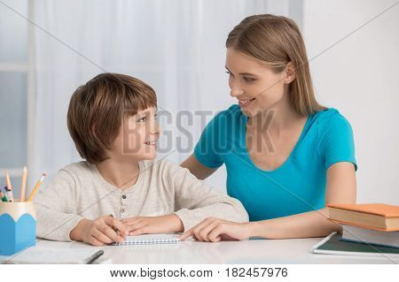 Mother young woman helping her child to do homework