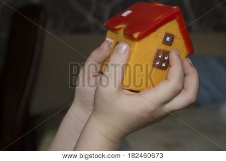 The child holds the toy house. Children's hands