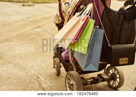 Outdoor crop shot of baby carriage with shopping bags. Copy space.