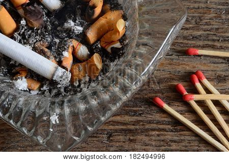 A close up image of a dirty ashtray and several wooden match sticks.