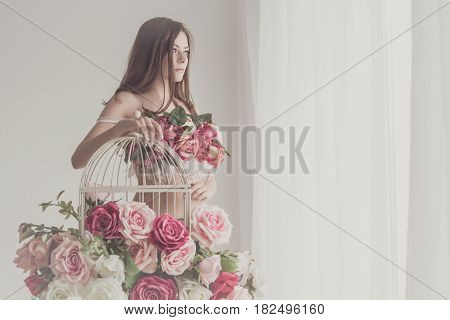 Girl in underwear. Bra of flowers. Spring mood. She stands by the empty cage near the window. Soft focus.