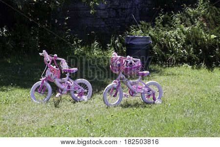 Laval, Quebec - June 14, 2015 -- Wide view of two vibrant pink children's princess bicycles parked in the grass in the Nature Park, Laval, Quebec on a sunny day in June.
