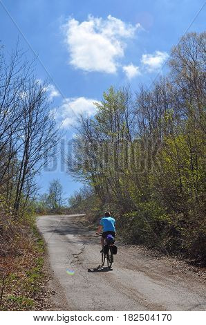 Men riding bicycle up mountain road in beautiful spring day. Bicycle tourism concept