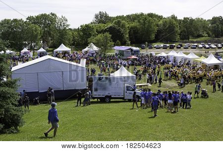 Laval, Quebec - June 14, 2015 - Landscape view of the large crowd of people in colorful t-shirts checking out the event tents attractions at the 
