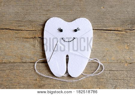 How to sew a felt tooth fairy. Step. Instruction for kids. Join the felt edges of felt tooth fairy with white thread. Vintage wooden background. Simple sewing projects and handmade crafts. Top view