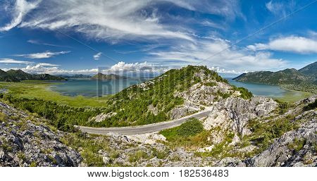 Panoramic view at the Montenegro part of Skadar mountain lake travel destination with highway. Sunny day and blue sky with clouds. Skadar lake is a national park nature place on Montenegro, Europe