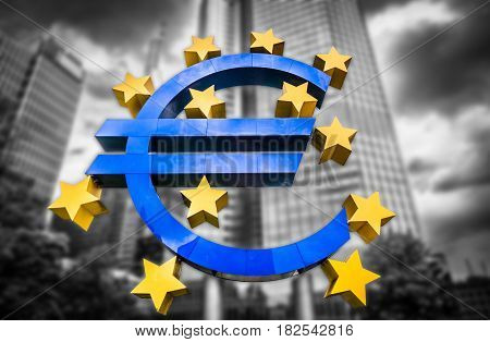 Euro sign at European Central Bank headquarters in Frankfurt Germany on abstract blurred background of dark dramatic clouds symbolizing a financial crisis
