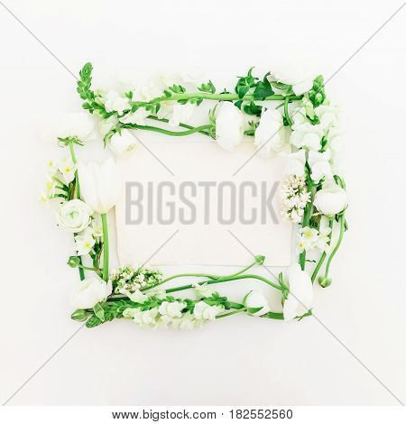 Floral frame of white ranunculus, snapdragon, lilac and tulip on white background. Flat lay, top view.