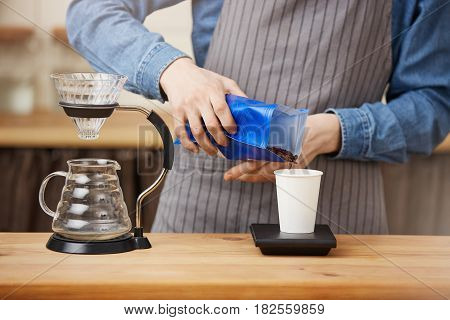 Closeup of male barista hands preparing pourover coffee, scaling coffee with digital scale. Organic coffee.