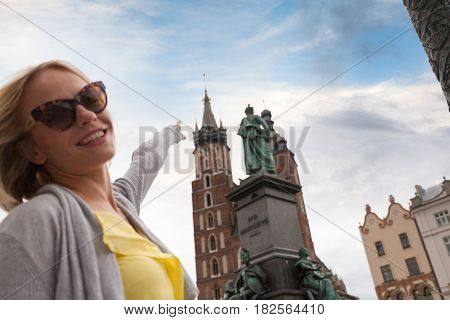 Female tourist in a yellow dress stands on a background of the church of St. Mary in Krakow. Basilica Mariacka. Krakow. Poland.