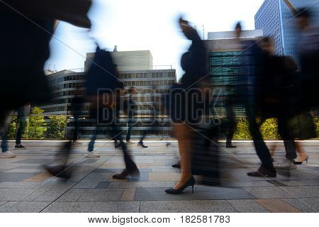 Blurred motion of businessmen and businesswomen commuting to work during busy rush hour in Tokyo, Japan