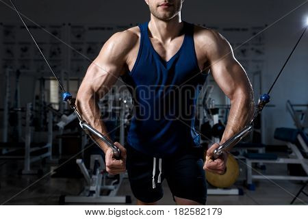 Athletic man in a T-shirt standing training on a exercise machine in the gym close-up
