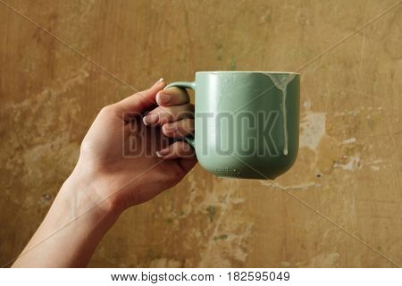 drink and refreshment female hand with blue cup with kefir butter milk yogurt or turkish drink ayran natural dairy product on beige wall background. Dieting and healthy eating