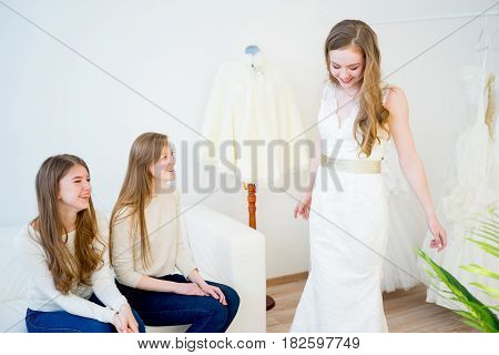 Bride trying on wedding dress with sales assistant
