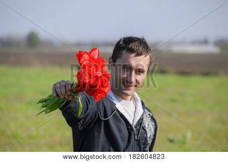 A Man In A Jacket On A Field Of Tulips. Glade With Tulips. A Man Is Tearing Tulips In A Bouquet