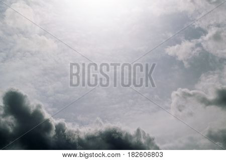 Grey sky Cirrus clouds and a dark gray-blue Cumulus clouds. Top the sun shines. There is a blue tint of the sky.