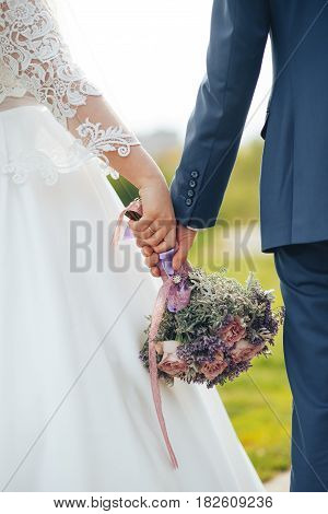 wedding bouquet in hands of newlyweds down