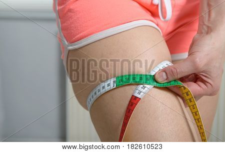 slim fit young woman measuring her thigh