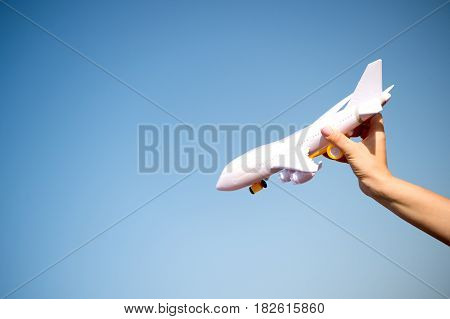 business traveling and vacation. freedom and inspiration. airmail and postal delivery concept. white toy plane in female hand landing or falling on sunny blue sky background copy space