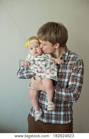 Beautiful happy smiling daddy of European appearance holds on the hands of a little baby girl