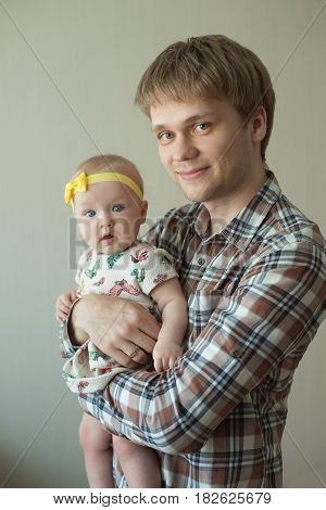 Beautiful happy smiling daddy of European appearance holds on the hands of a little baby girl
