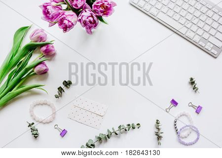 Spring pink flowers on workdesk at home ofiice white background top view mockup