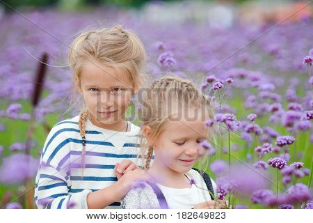 Little adorable girls walking outdoor with flowers