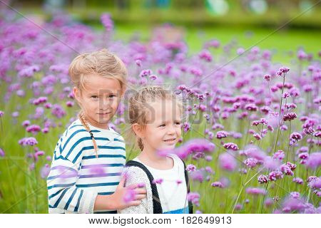 Little adorable girls walking outdoor with flowers