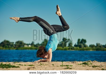 Young flexible athletic woman in yoga pose outdoors