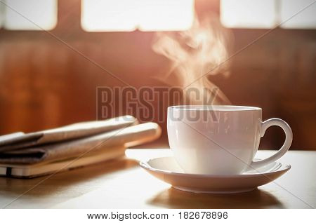 coffee cup with newspaper on the table coffee shop background warm tone