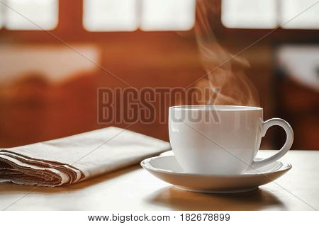 coffee cup with newspaper on the table coffee shop background warm tone
