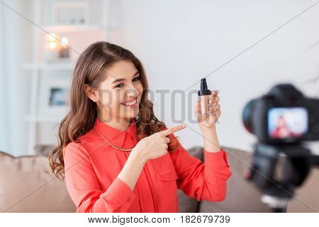 blogging, technology, videoblog, makeup and people concept - happy smiling woman or beauty blogger with foundation and camera recording tutorial video at home