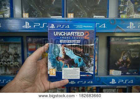 Bratislava, Slovakia, circa april 2017: Man holding Uncharted 2 Among thieves videogame on Sony Playstation 4 console in store