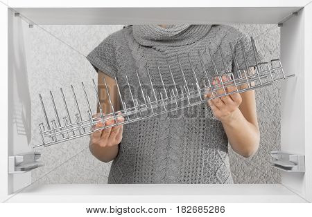 hands assembling dish rack inside kitchen cupboard