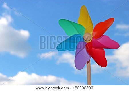 colorful pin wheel against blue sky with white clouds