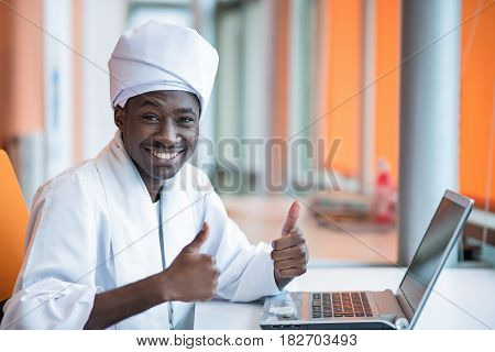 Sudanese business man in traditional outfit using mobile phone in office.