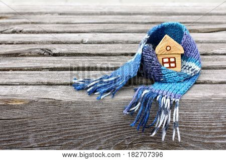 Small house in a warm scarf on a very old wooden surface / warming atmosphere for living