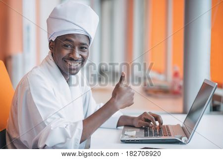 Sudanese business man in traditional outfit using mobile phone in office.