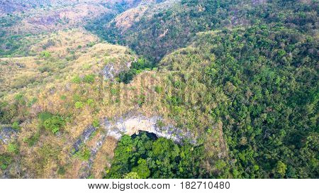 aerial photography above amazing cave. Tham Than Lod Yai is the big cave and have one hole on the top of the cave. it is a short cave there have waterfall pass inside through to another cave