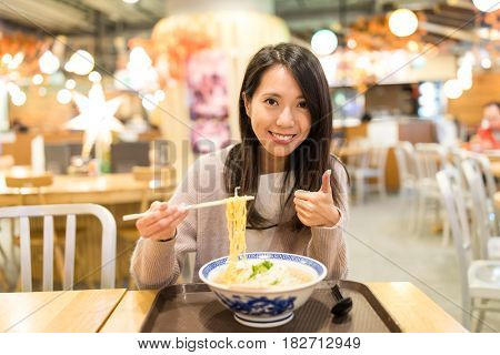 Woman enjoy her ramen and showing thumb up in japanese restaurant