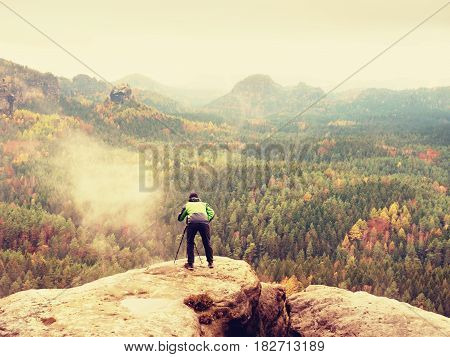 Hiker With Camera On Tripod Takes Picture From Rocky Summit. Alone Photographer At Edge Photograph L