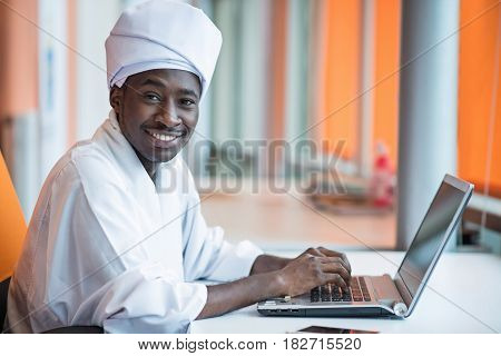 Sudanese business man in traditional outfit using mobile phone in office.