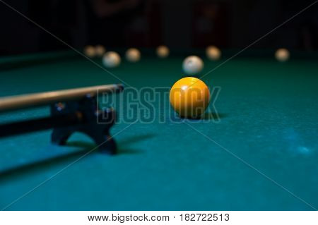 Billiard cue is aiming to take the snooker shot. Green table with balls on background