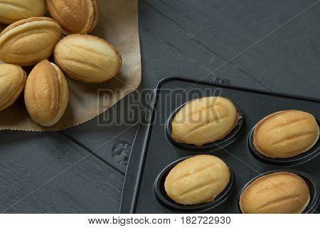 Cookies with condenced milk and filled baking-mold on wooden background