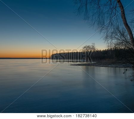 sunset over the frozen lake and forest coast