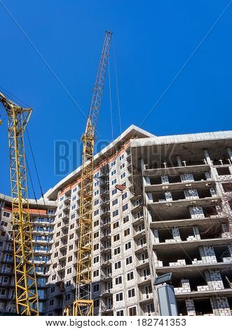 Two yellow crane building a multistory residential building blocks.