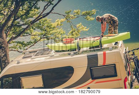 Men Installing Kayak on the RV Camper Van. Preparing For the Next Motorhome Trip.