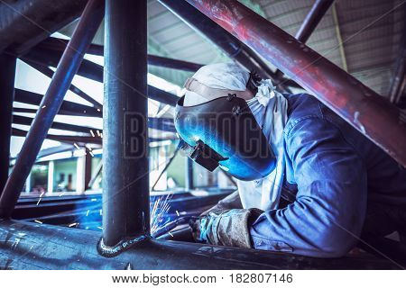 Industrial Worker at the factory welding welding steel pipe structure