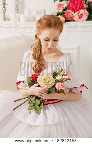 Sweet ballerina in a stage costume holds a bouquet of spring flowers. Retro dress. A gift from a fan.